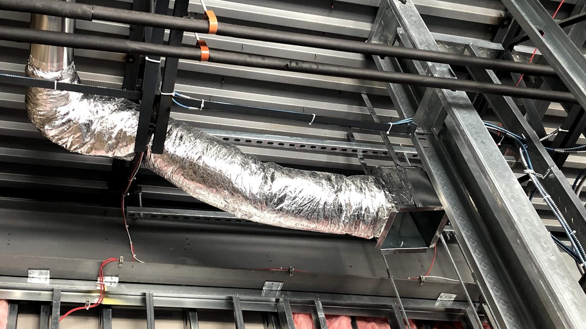 Above-ceiling commercial HVAC ductwork, piping, supports, and wiring during a mechanical rough-in.