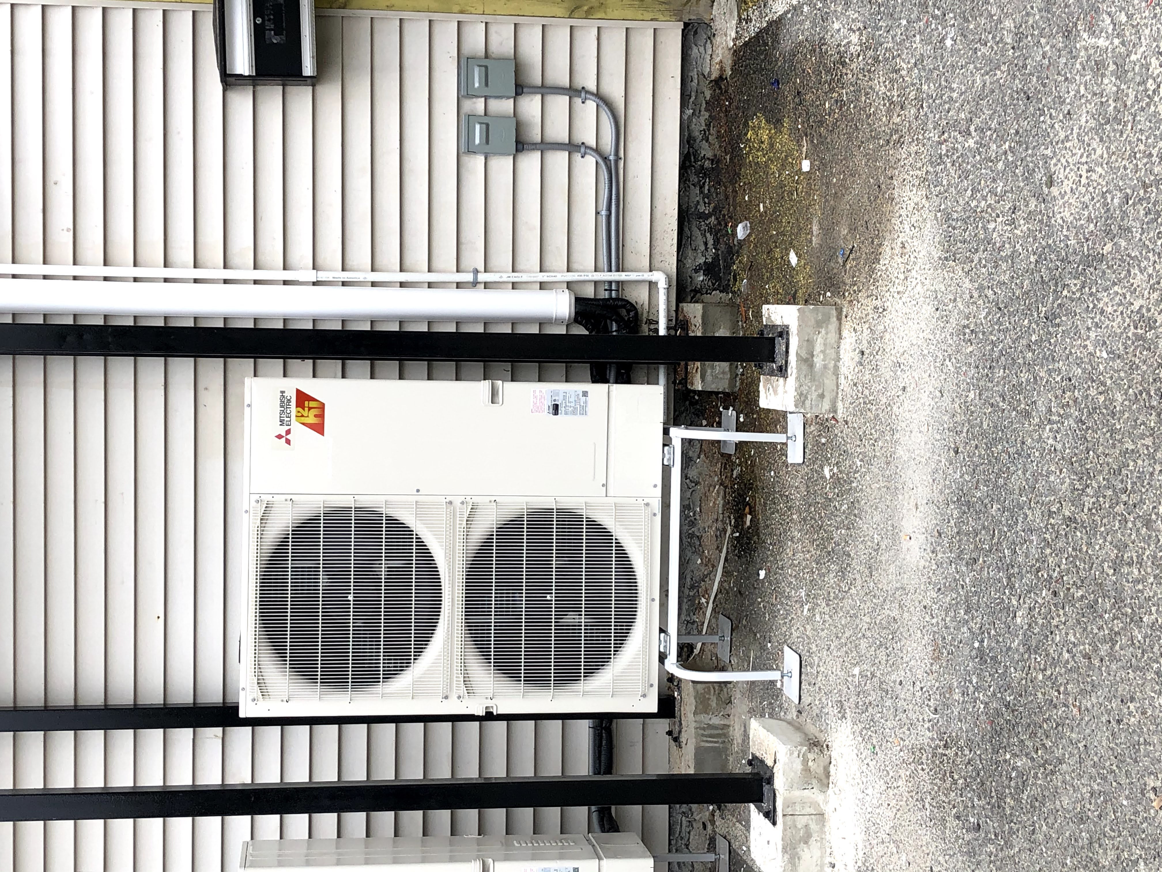 Mitsubishi Electric outdoor mini-split heat pump condenser installed outside a building by New Generation HVAC.