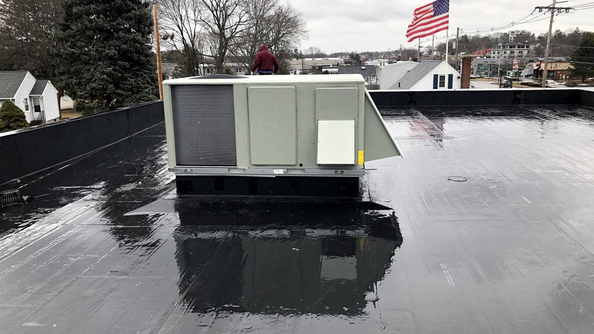 Commercial rooftop HVAC unit on a flat roof with a technician nearby.