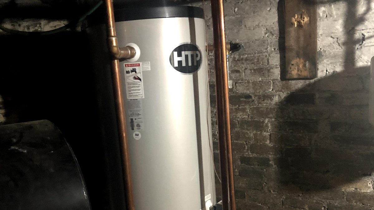 Basement mechanical room with copper piping and a water heating tank in an older Merrimack Valley home.